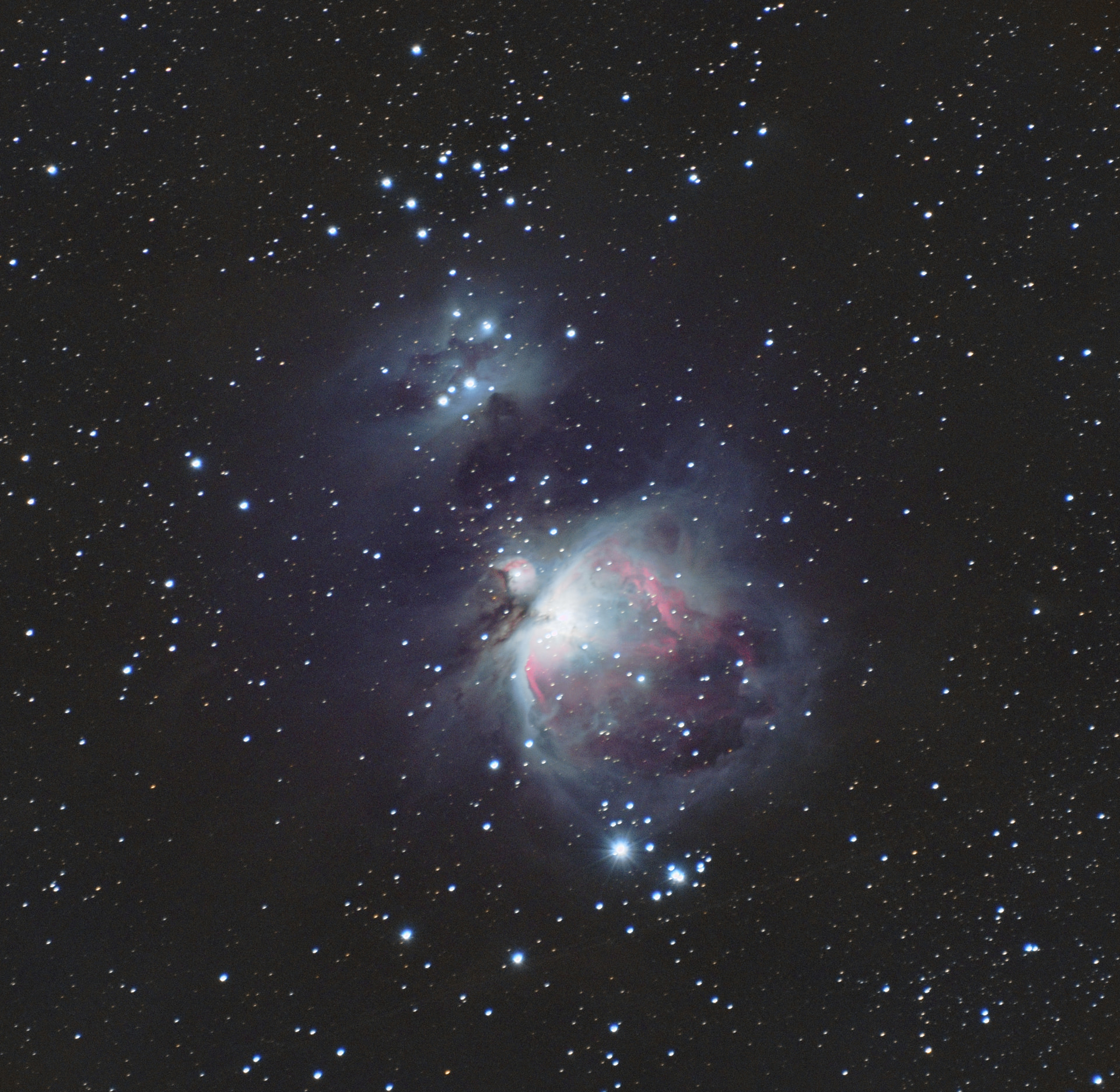 The Orion Nebula glowing pink beside the blue Running Man Nebula, set among scattered stars